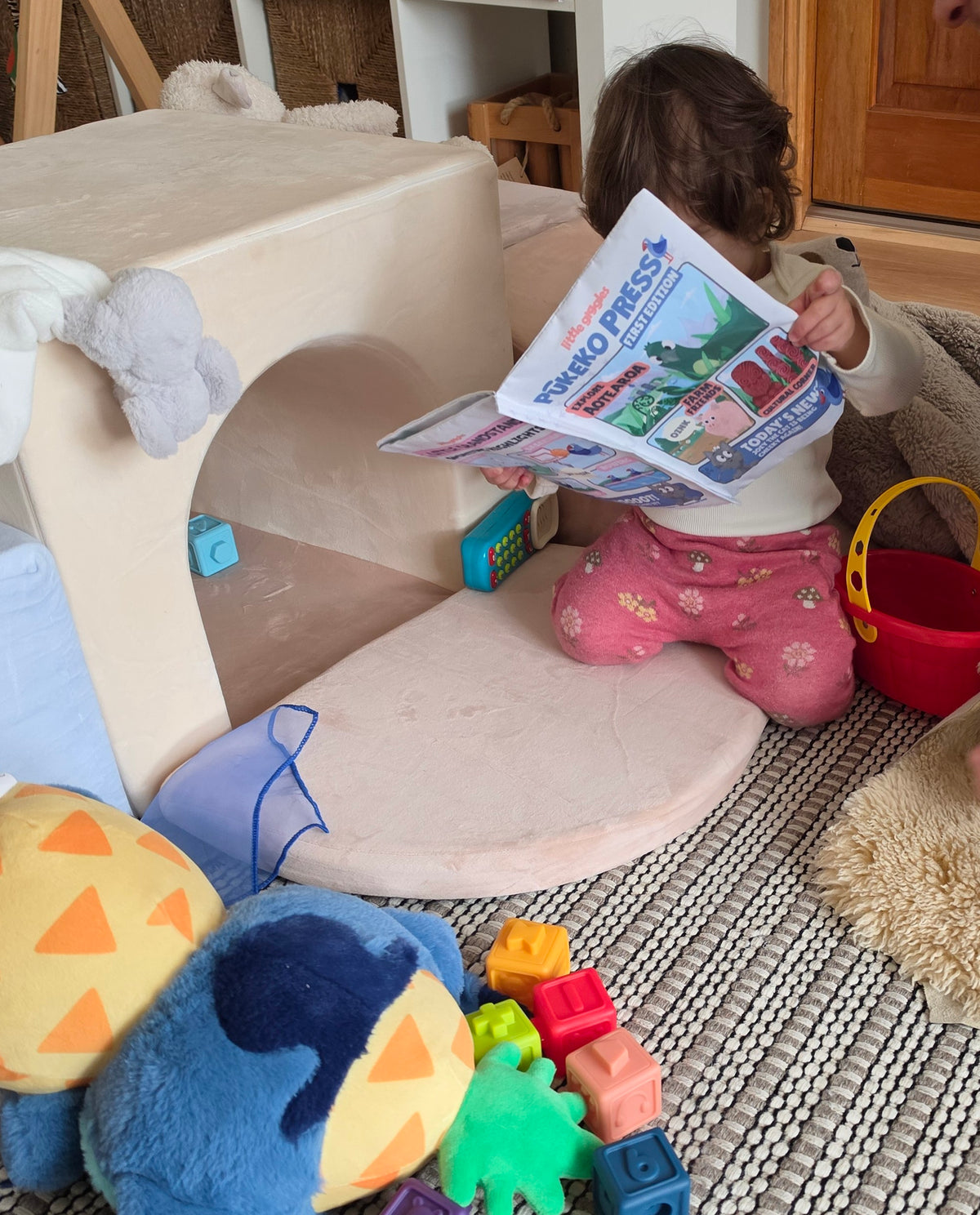 Baby playing with Pūkeko Press sensory toy and colourful toys