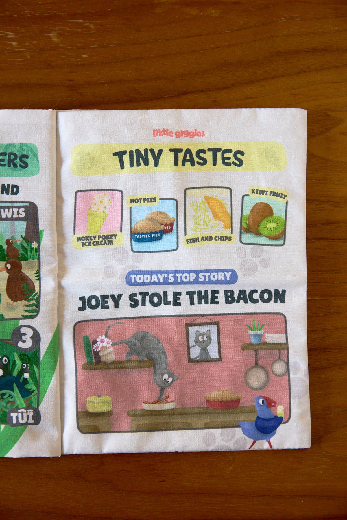 Pūkeko Press sensory toy open to illustrated pages on wooden table